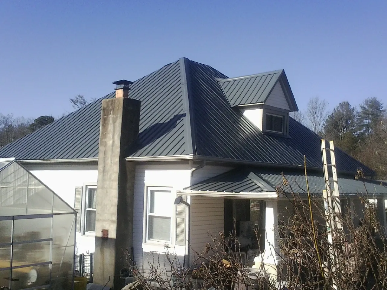 Dark blue standing seam metal roof on a white farmhouse with dormer — Slate & Tile Roof Repair by Roofing Brothers in Fryeburg
