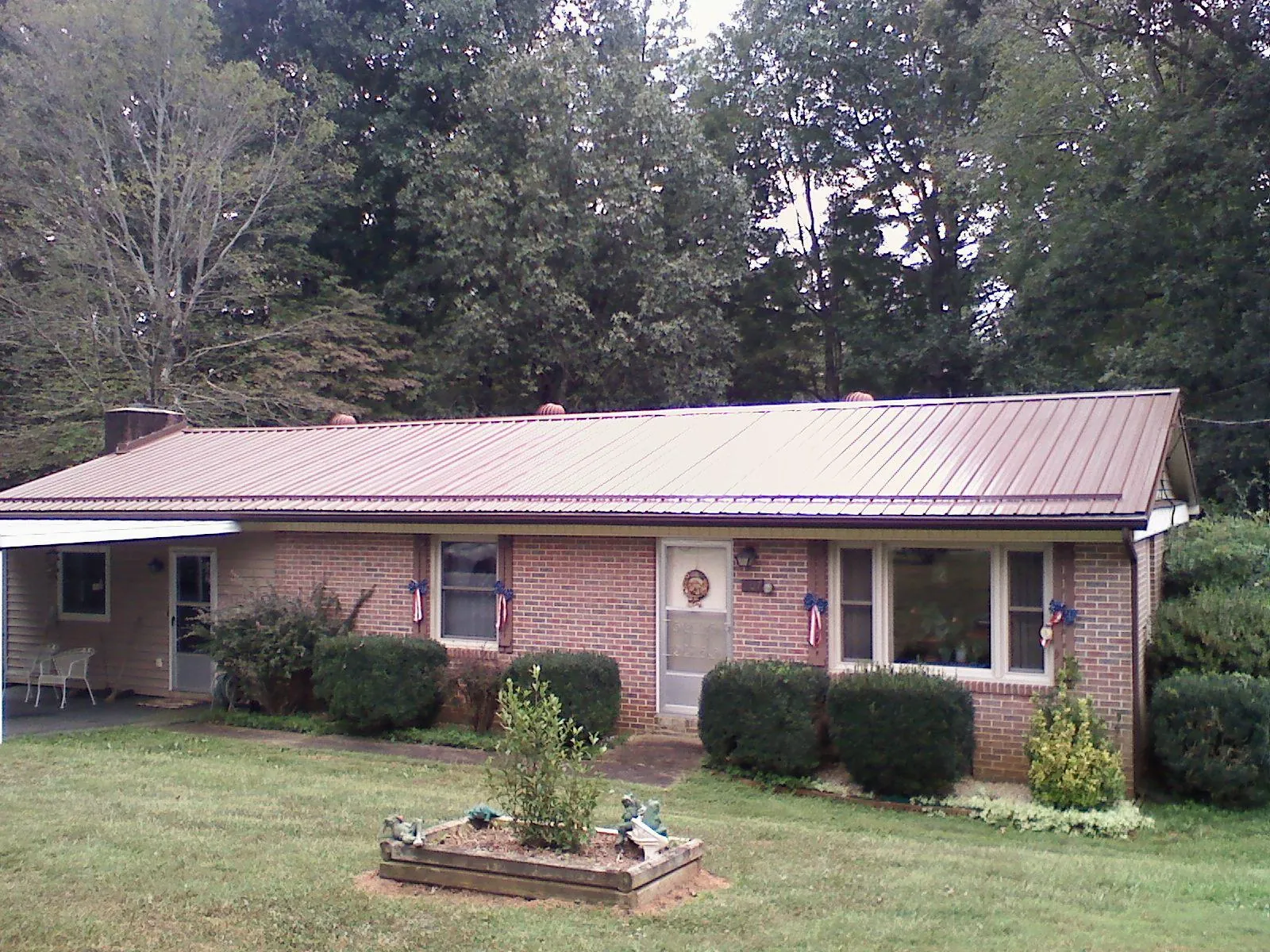 Bronze metal roof on a brick ranch home with a carport in Fryeburg