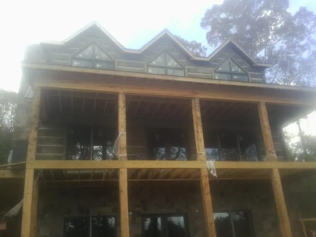 Dormers and porch framing on a large log home under construction — Roof Coating work by our crew in Fryeburg