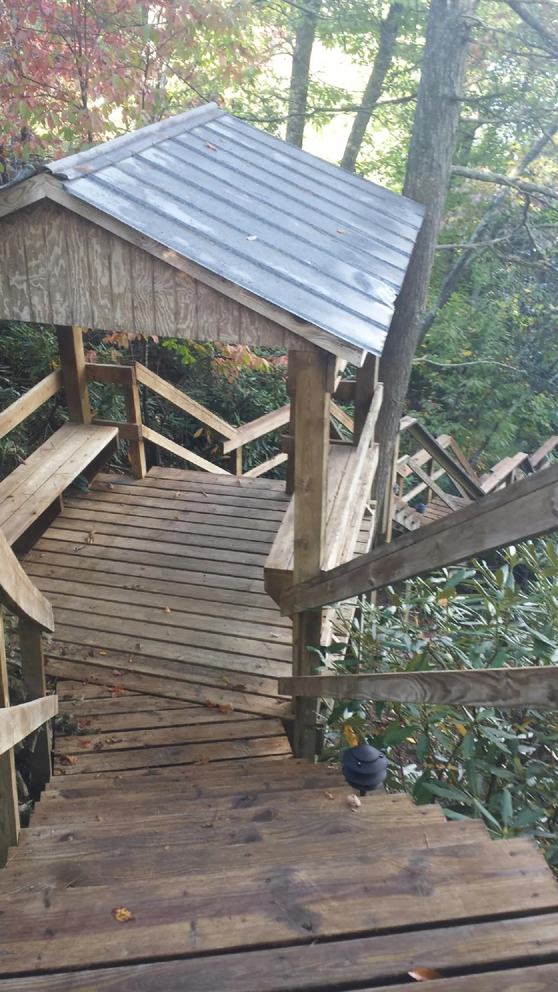Metal roofed shelter over wooden steps on a wooded walkway — Skylight Repair & Installation work by our crew in Fryeburg